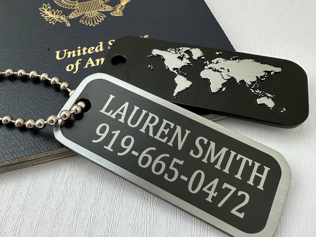 Custom black and silver travel tag featuring a raised world map design on the back, exemplifying a blend of style and functionality