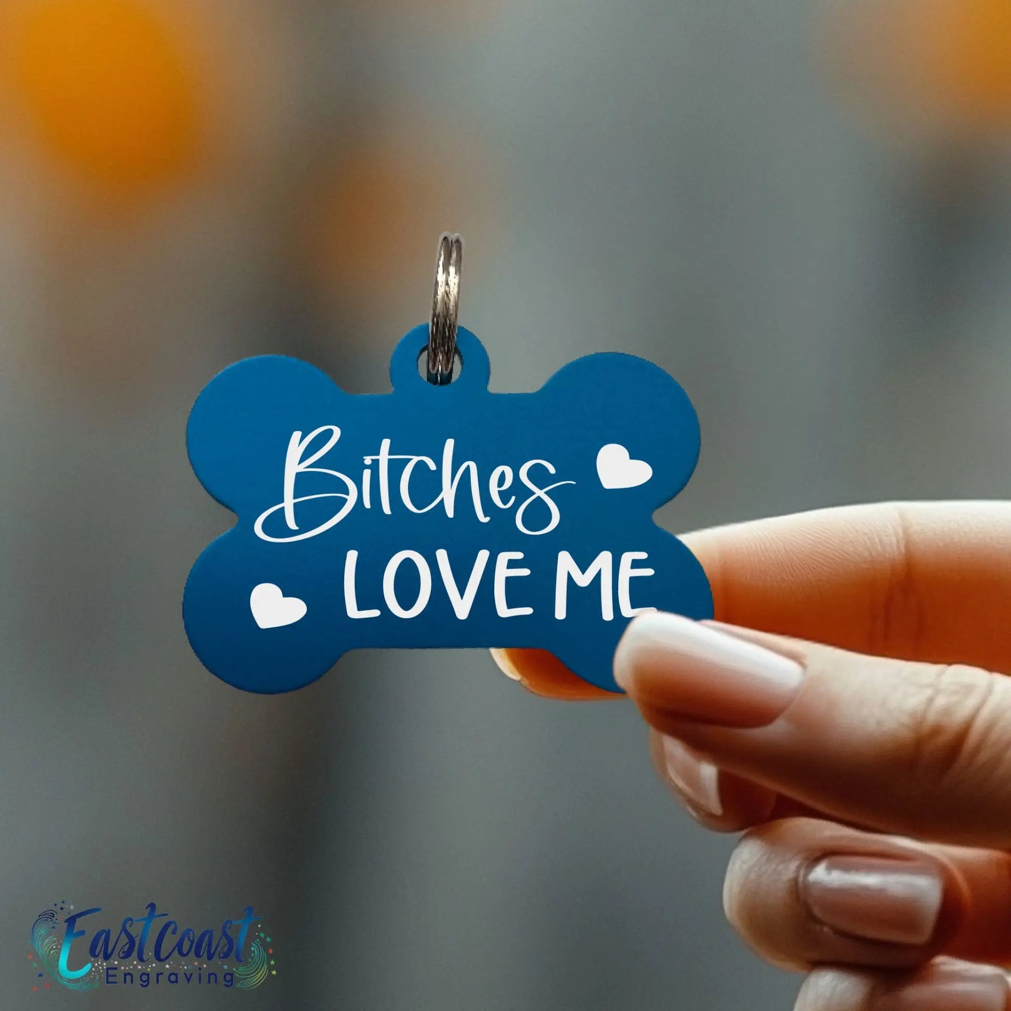 Blue bone-shaped dog tag with playful “Bitches Love Me” lettering