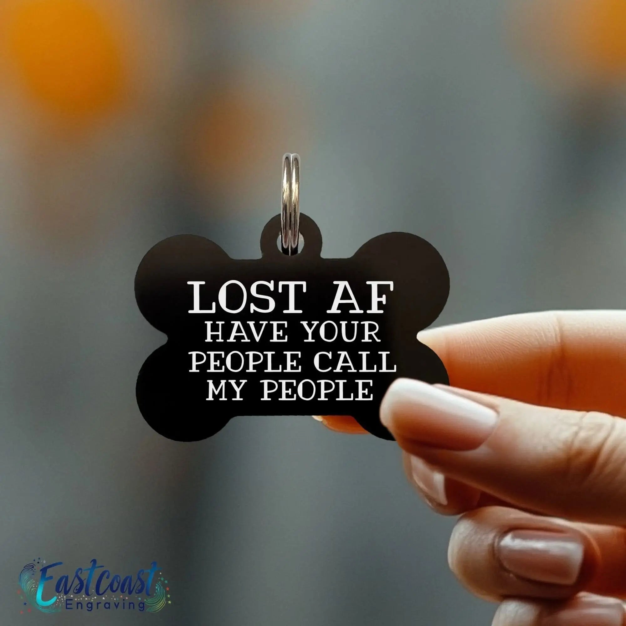 Funny black bone-shaped dog ID tag engraved with “Lost AF Call My People” hanging from a dog collar