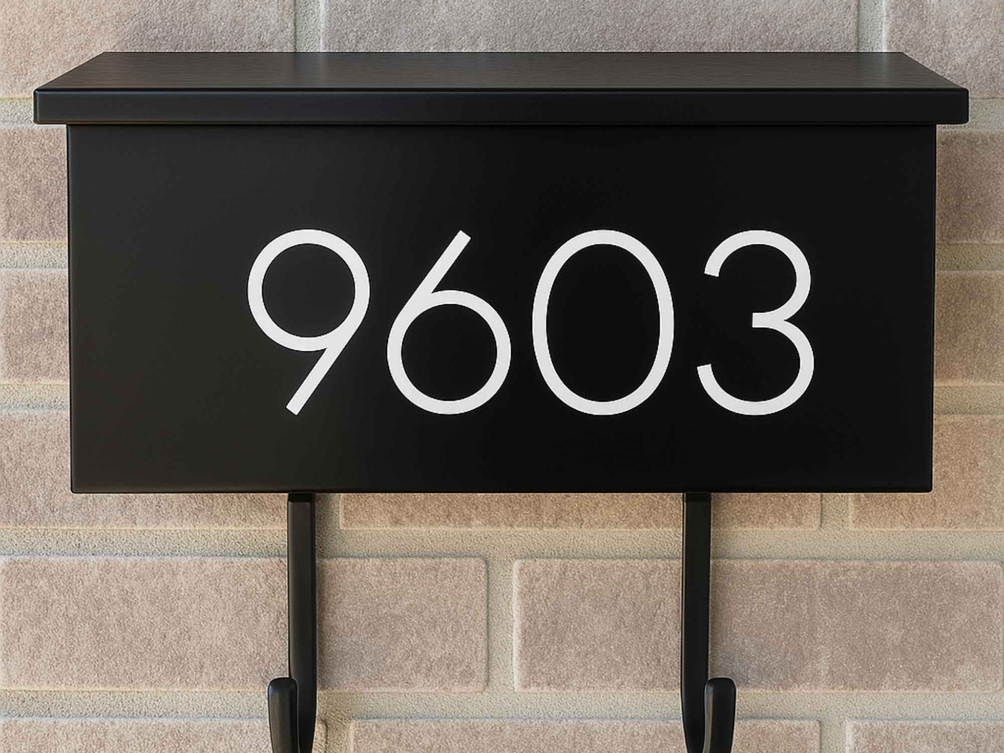 Vinyl mailbox number decal on a black wall-mounted mailbox in modern sans serif font
