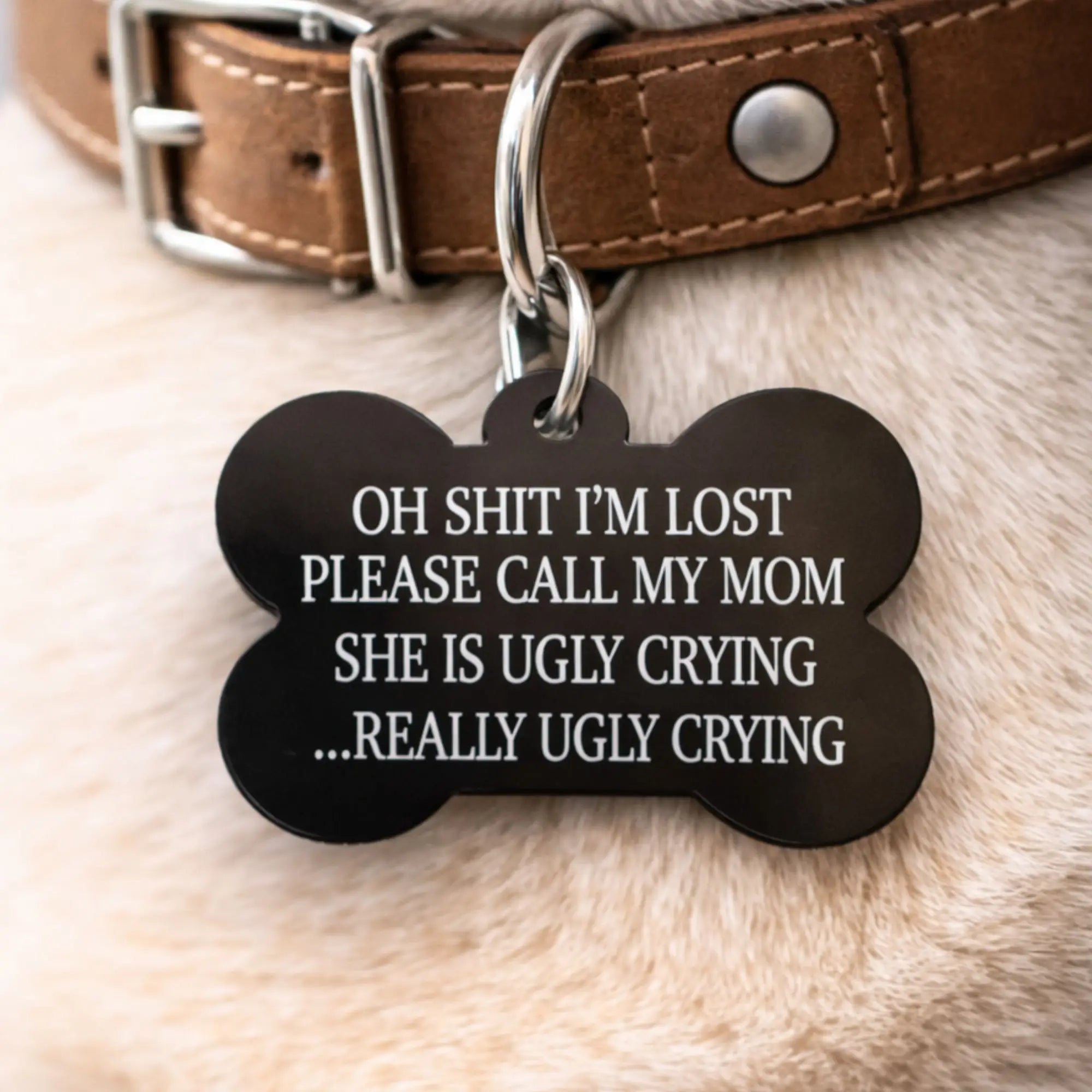 Black bone-shaped funny dog ID tag reading “Oh shit I’m lost, please call my mom” shown in a close-up product photo