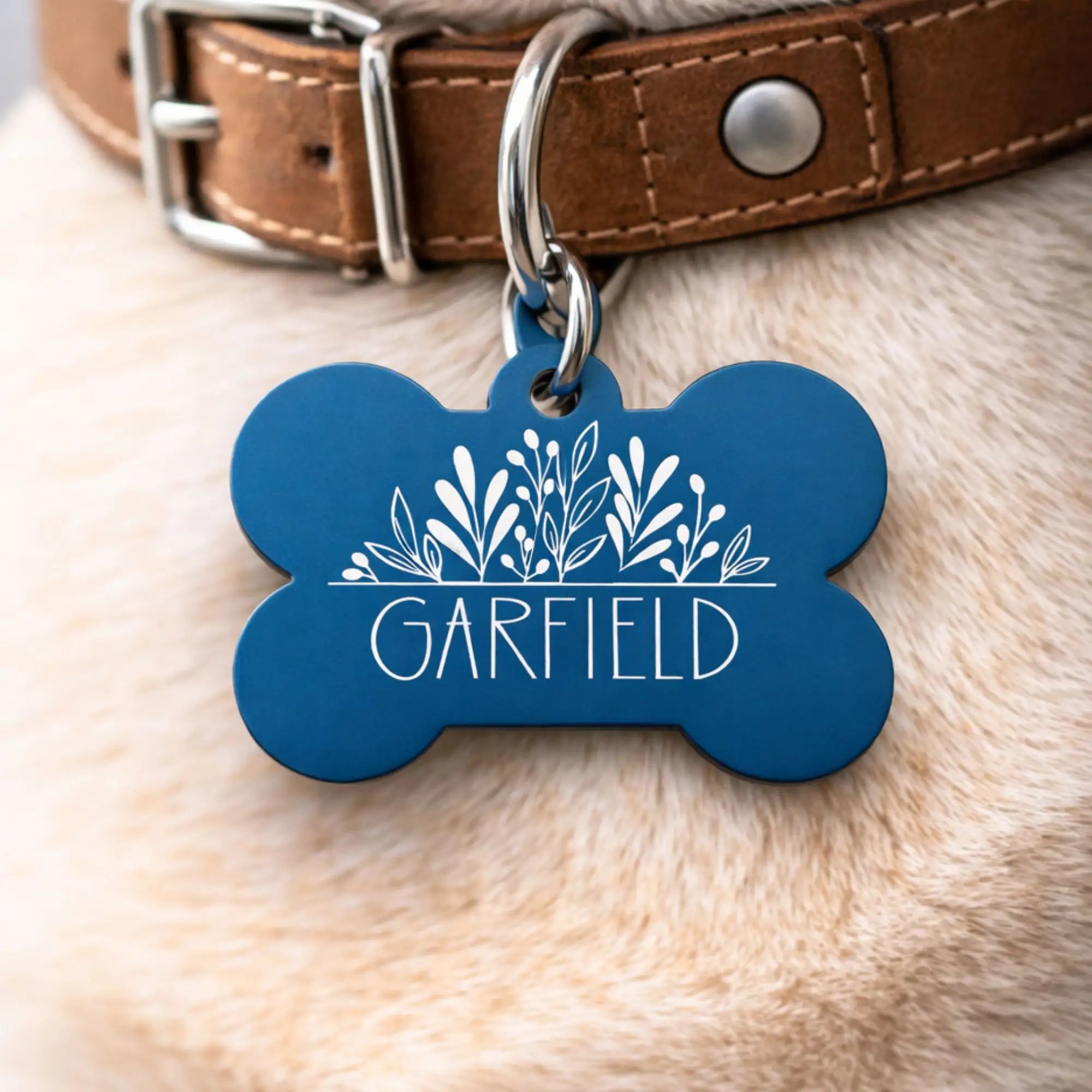 Personalized dog name tag with decorative floral design and custom pet name engraved on a bone-shaped ID tag