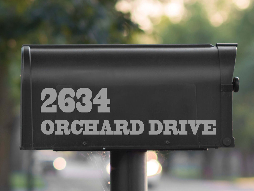 Modern black mailbox featuring reflective silver decal numbers '2634' and street name 'ORCHARD DRIVE' in a clean, sans-serif font