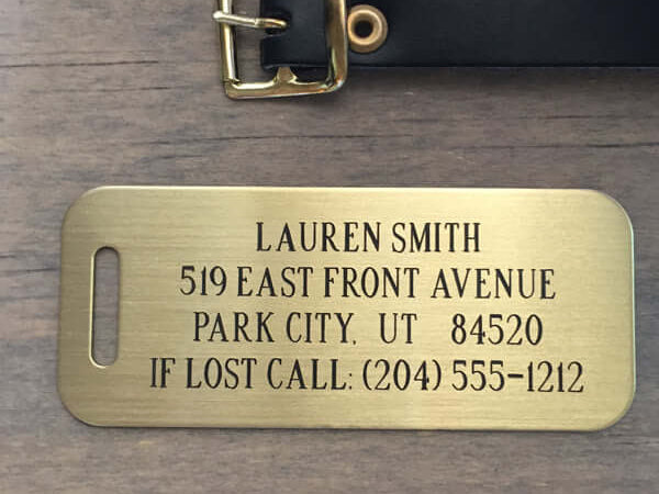 Custom brass luggage tag with plain brass engraved lettering, durable design for travel.