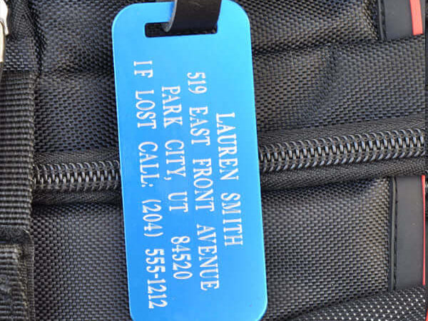 Custom blue luggage ID tag with silver engraving and leather strap for travel gear