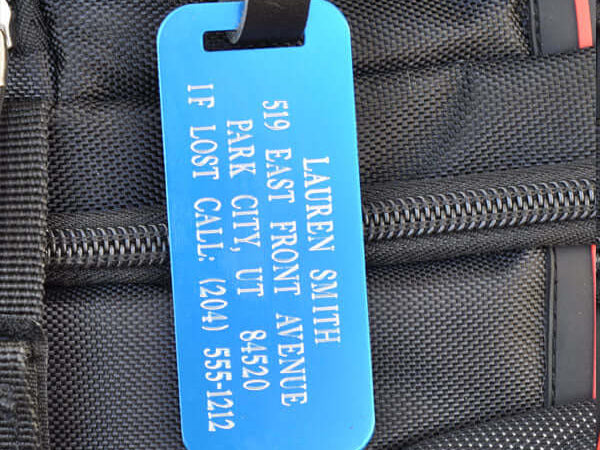 Custom blue luggage ID tag with silver engraving and leather strap for travel gear