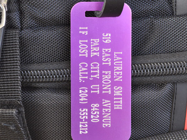 Custom engraved purple travel tag securely attached to suitcase handle