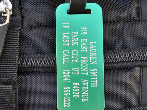 Custom green engraved luggage tag with leather strap for travel, backpacks, and personalized gear identification.