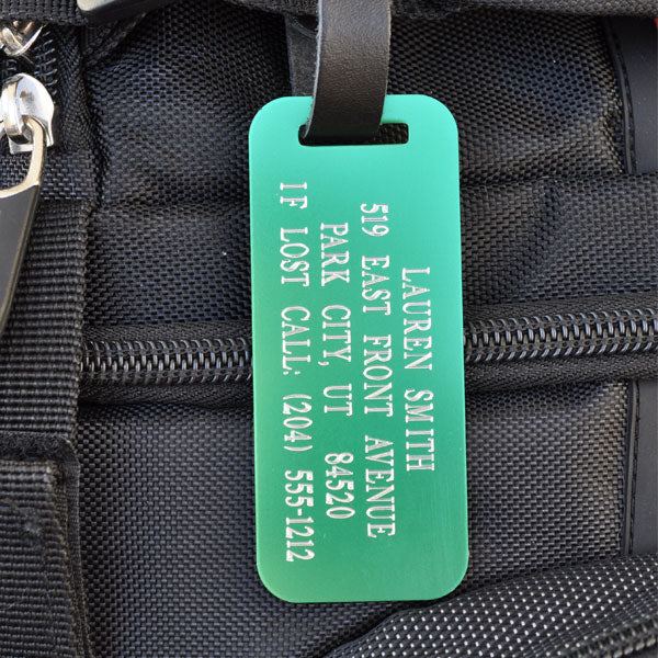 Custom green engraved luggage tag with leather strap for travel, backpacks, and personalized gear identification.