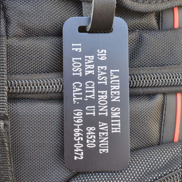 Custom engraved black aluminum luggage tag with silver lettering and leather strap