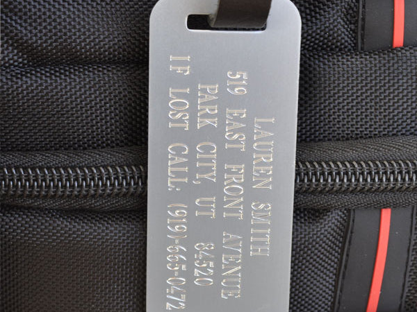 Custom engraved silver luggage tag with black leather strap for personalized bag identification, ideal for air travel, work gear, and secure ID.