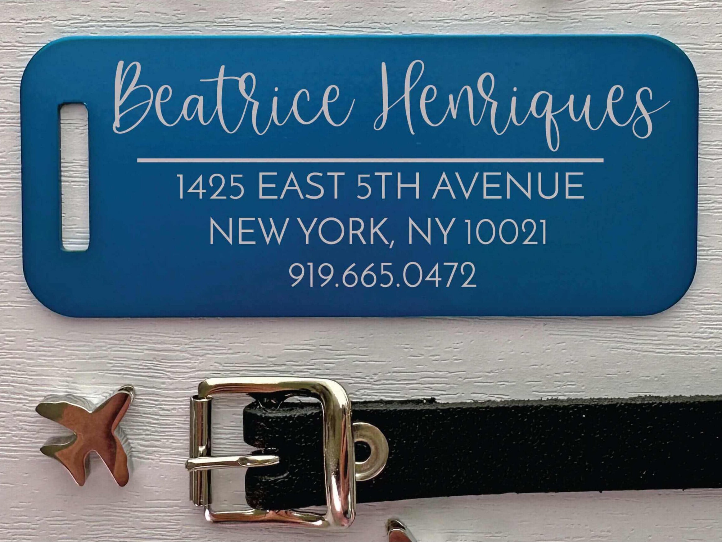 Blue aluminum luggage tag personalized with engraved travel info